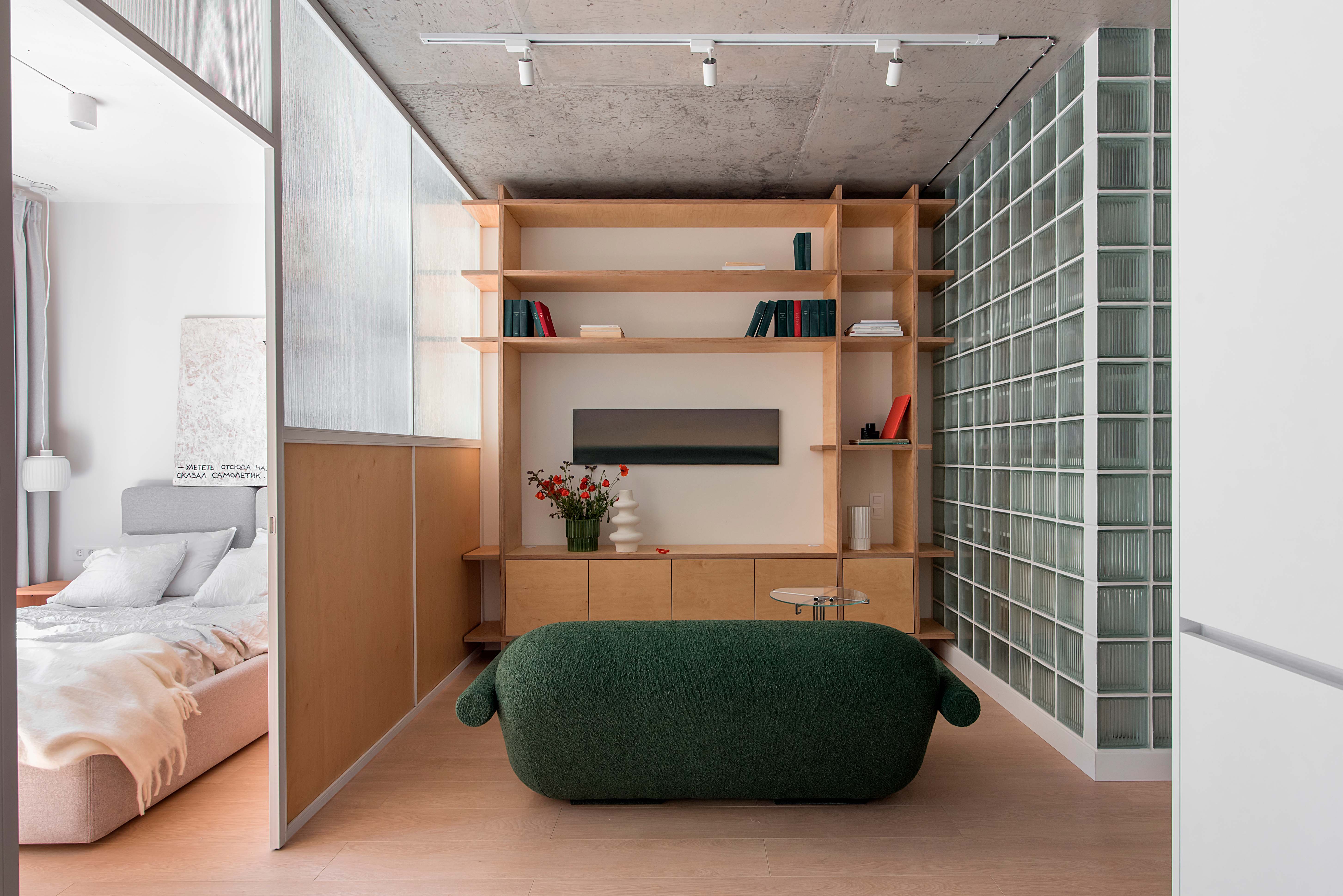 a small apartment with a glass divider between bedroom and living space, and a glass block wall