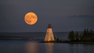 The July Supermoon rises near the Kidston Island Lighthouse on Kidston Island, located in the Bras d'Or lakes in Baddeck, Nova Scotia, Canada. Kidston Island is an uninhabited island in the Bras d'Or Lakes in Baddeck, Nova Scotia.