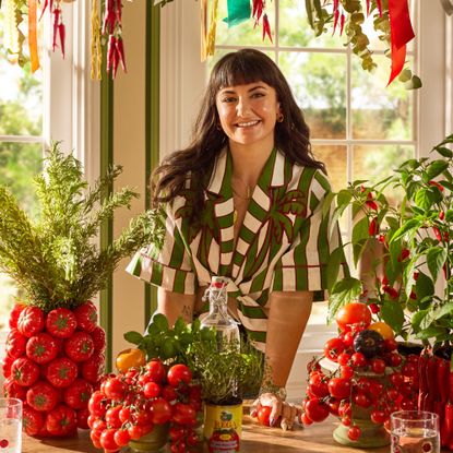 Interior Design Masters winner Lia Gold with a dining table in front of her decorated with a tomato vase and a chilli planter from her collection for Next