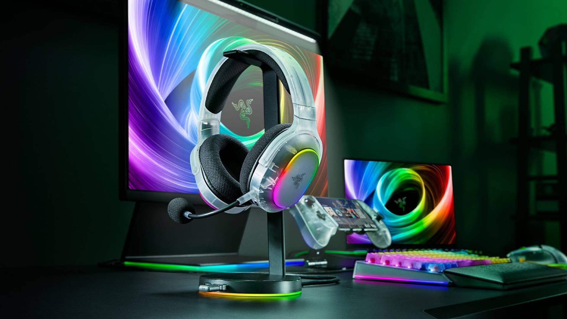Promo image showing a translucent Razer headset sitting on a stand, with a monitor and matching accessories behind it.
