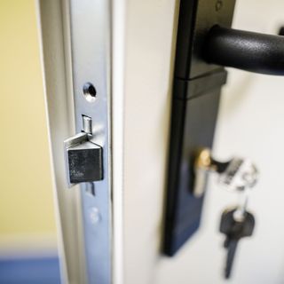 silver lock mechanism on a front door with a black handle and a set of keys in it