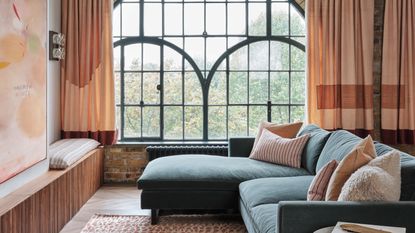 a living room with a large window with peach curtains