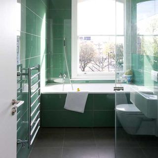 bathroom with bathtub and green tiles