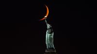 A ten percent illuminated waxing crescent moon sets behind the Statue of Liberty on October 13, 2026, in New York City.