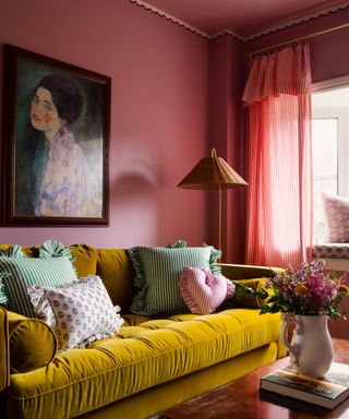 living room with dark pink walls and mustard sofa with colorful patterned cushions