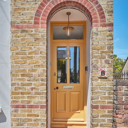 A yellow front door with an arch-shaped entrance to the porch