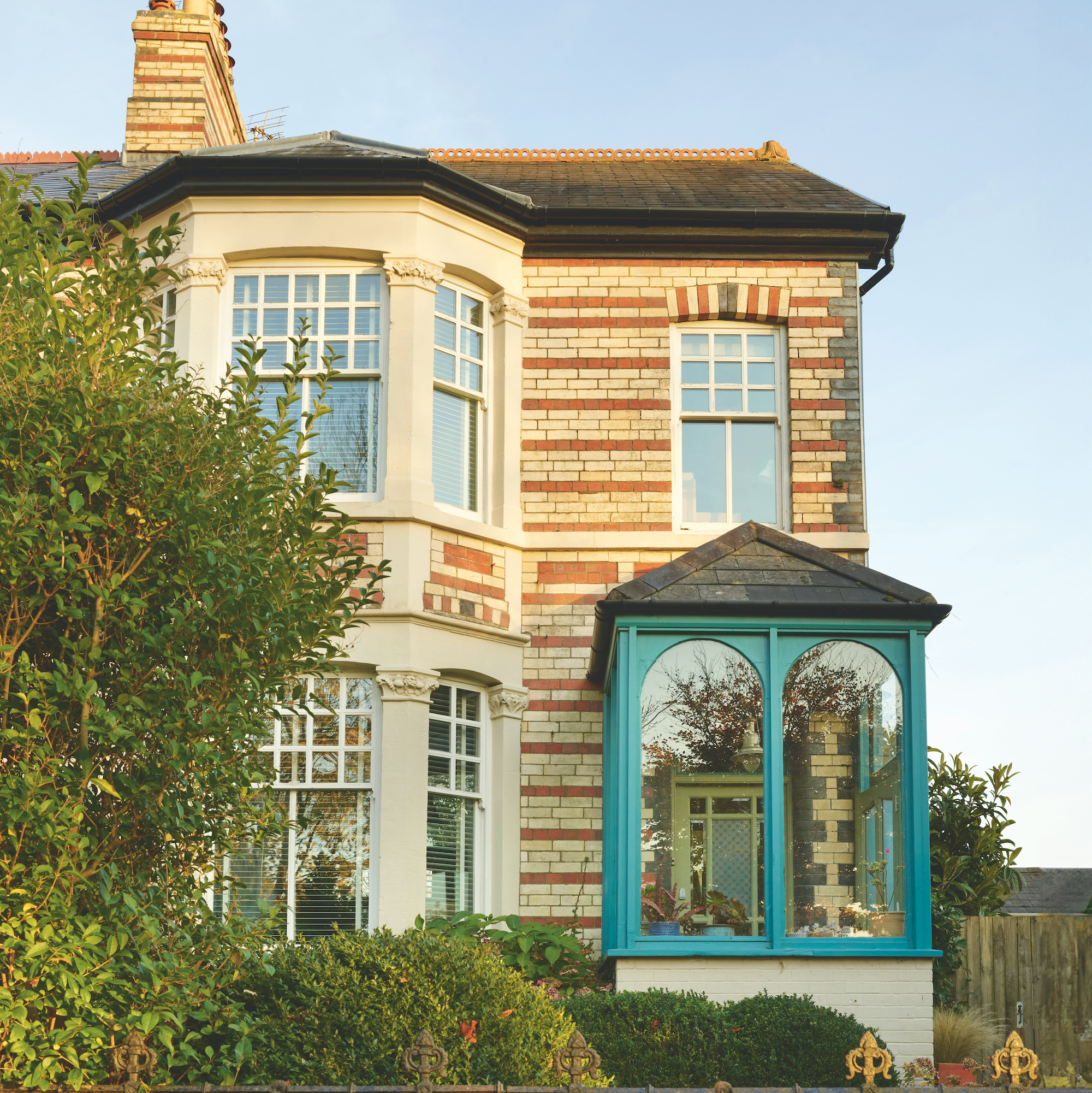 exterior of semi detached Victorian house in Wales with a blue painted exterior glazed porch and two tone brickwork