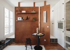 small modern apartment with a wooden divider in the middle with shelving and art on it