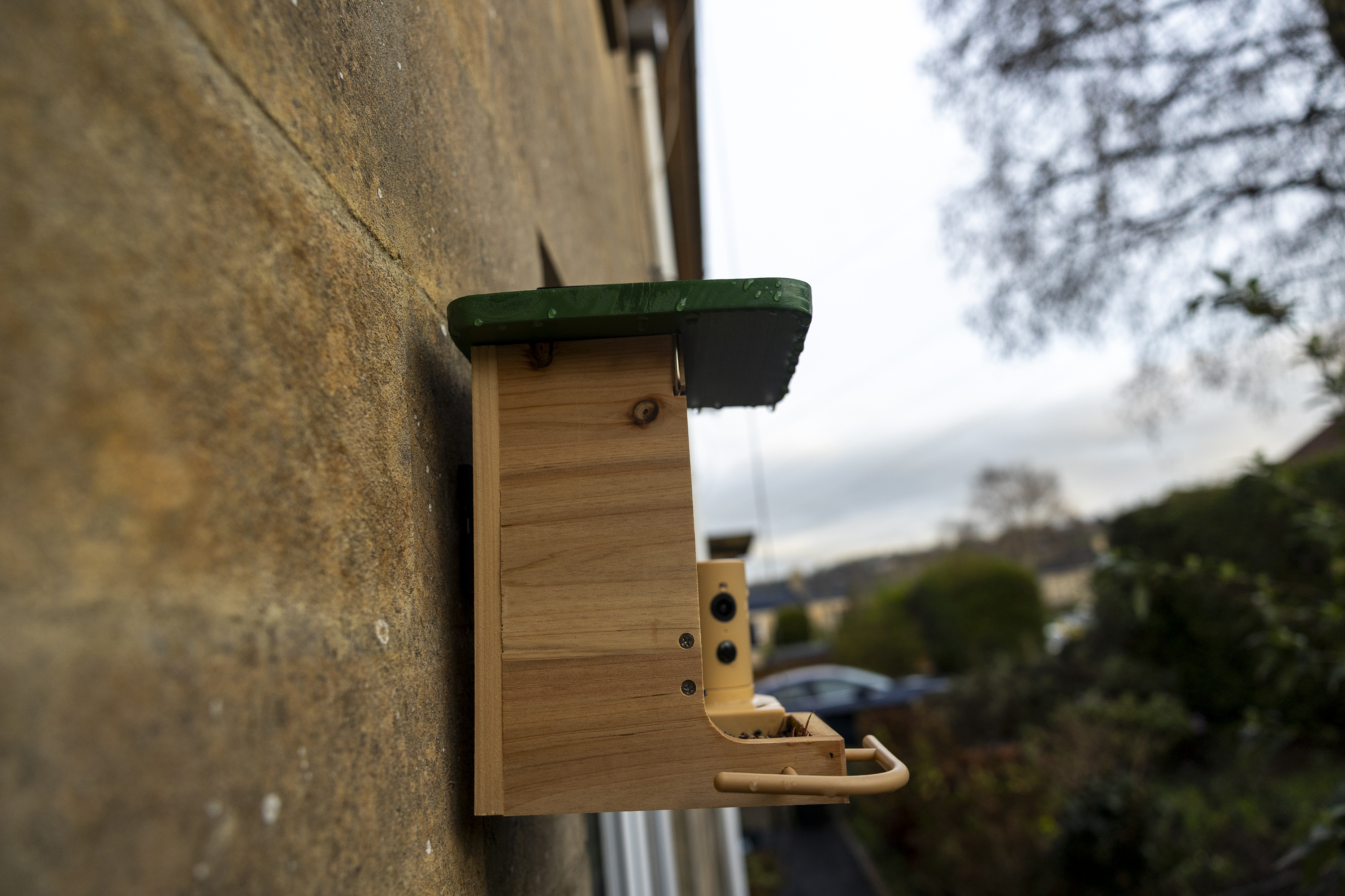 The Birdfy Wood feeder on a stone wall