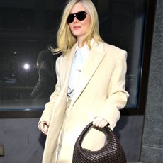 Elle Fanning wears a yellow coat, yellow trousers and carries brown Veneta Bottega Veneta bag.