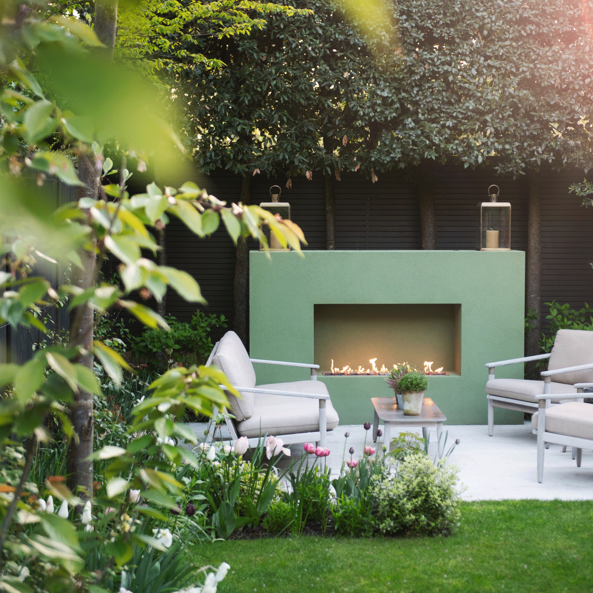 a garden with a patio area and large green outdoor fireplace and seating in front