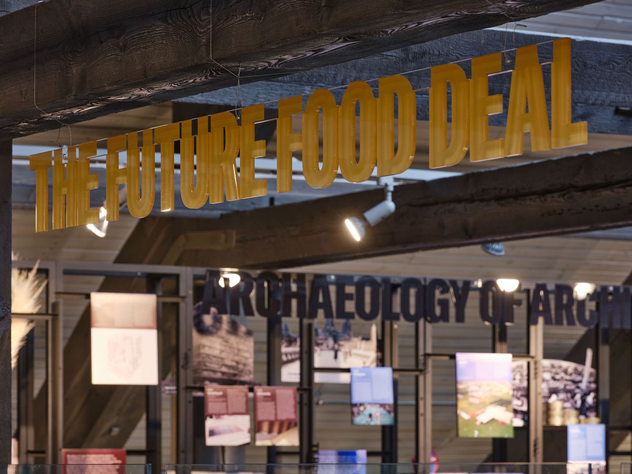 View of exhibition in tallinn with yellow lettering, glass front and blurred background of display