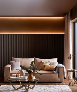 A modern neutral living room with upholstered two seater sofa and LED strip lighting on back wall