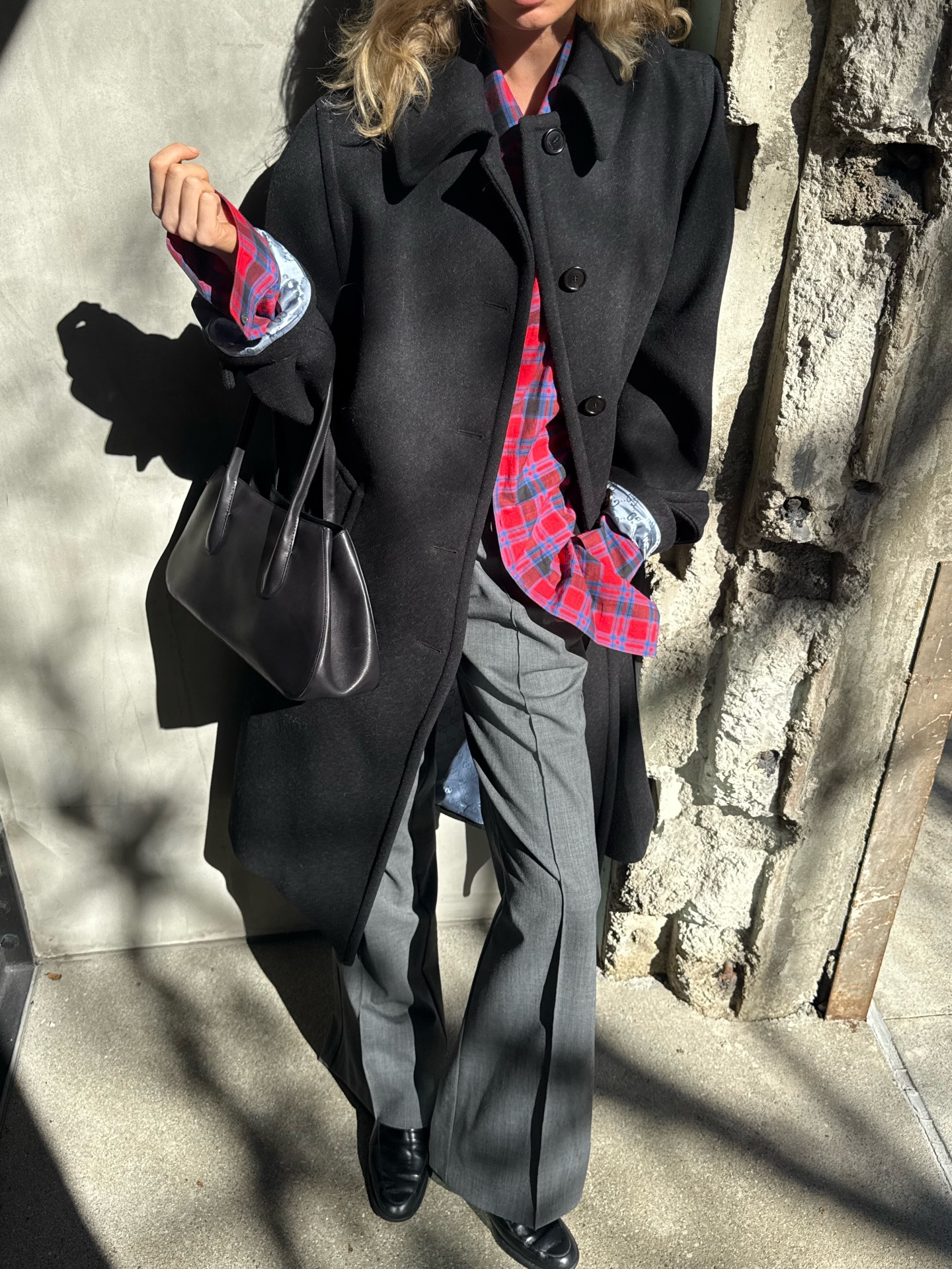 Elsa Hosk wearing a red flannel The Row shirt with a black jacket and gray tailored trousers.