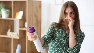 Woman holding her nose in smelly room