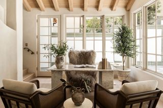 A home office with exposed beams, a shaggy armchair and two comfy seats