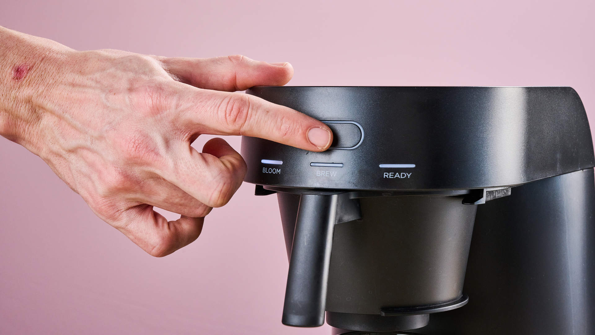 A man presses the button to start the Ratio Four's brew cycle.