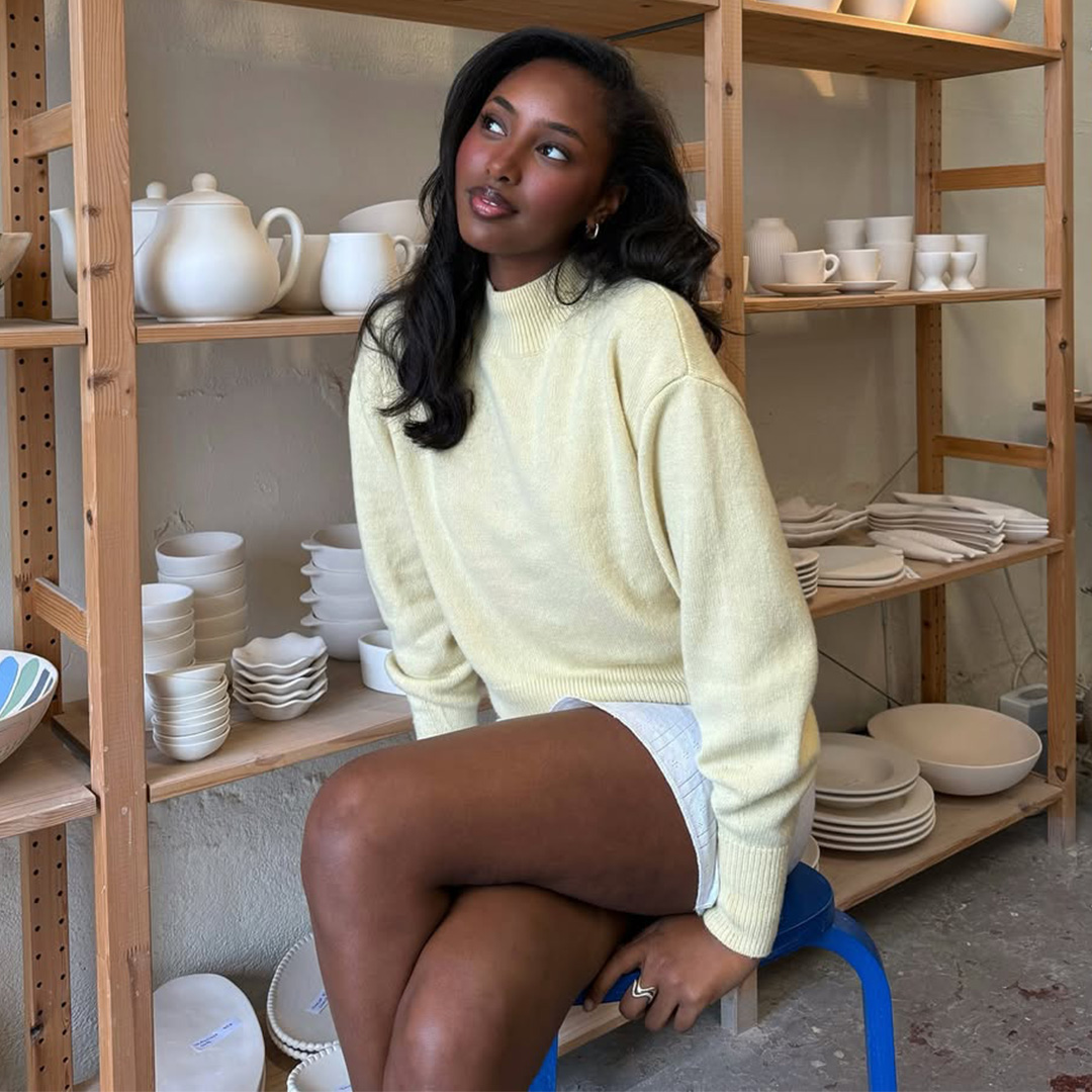 Rayan Xasan wears a butter yellow sweater at a pottery studio in Lisbon, Portugal