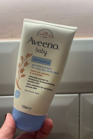 una mano sosteniendo la crema aveeno baby dermexa