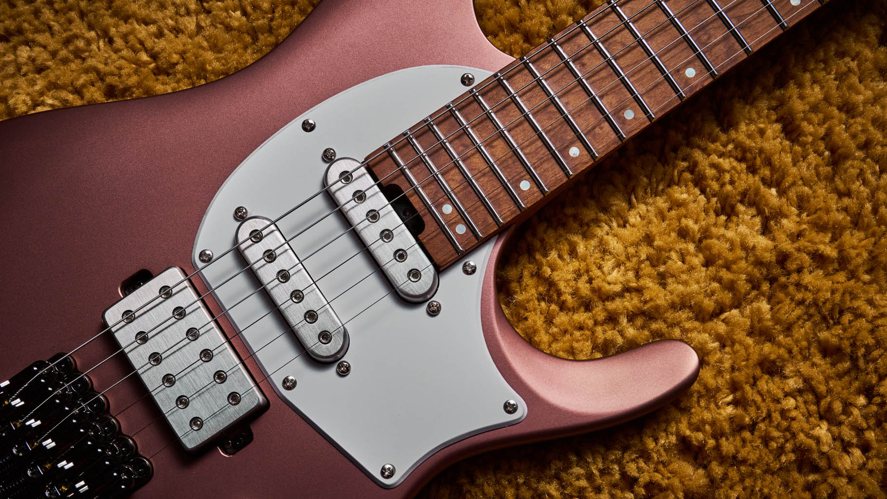 Ibanez Q54W: the headless electric guitar is finished in Copper Metallic Matte and photographed against a thick light-tan colored carpet.
