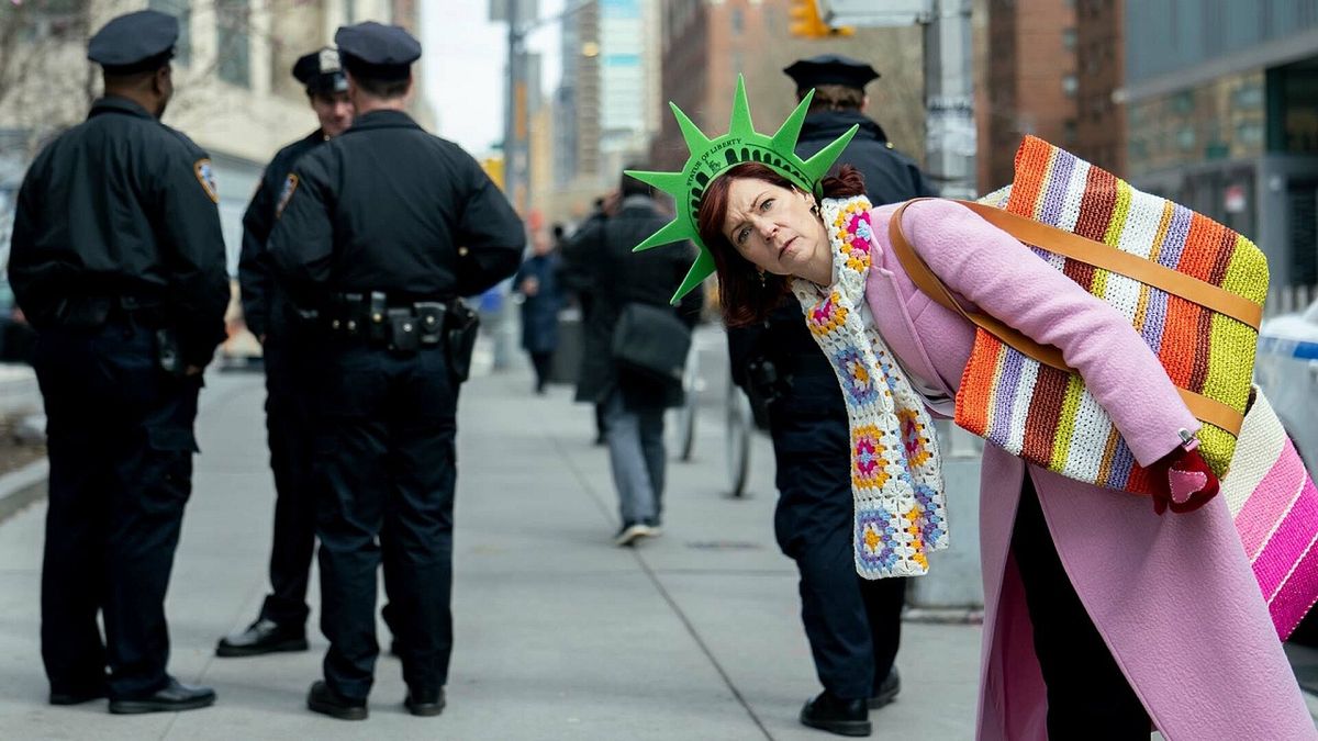 Elsbeth Tascioni (Carrie Preston), poses in a novelty Statue of Liberty hat behind NYPD officers while looking to camera in a promo image for CBS&#039; Elsbeth