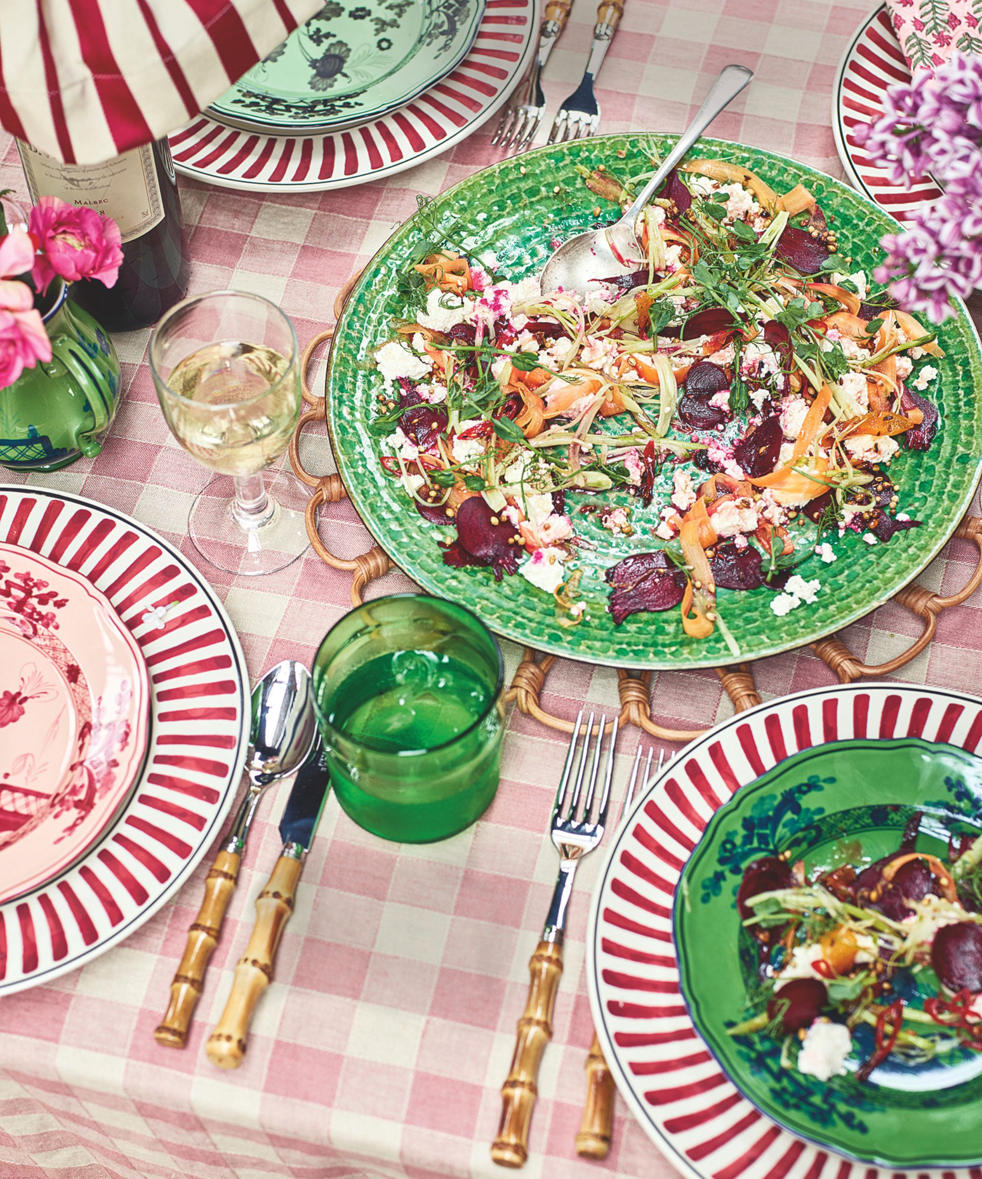 Pickled vegetables and ricotta on a green plate on a pink and white gingham tablecloth with green and pink accessories