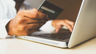 person holding credit card while shopping online