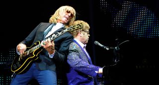 Elton John and Davey Johnstone perform at the piano during their 2012 tour, with Johnstone playing the Les Paul Custom 'Black Beauty' that John originally bought for himself, but gave it to Johnstone after the band had all their gear stolen.