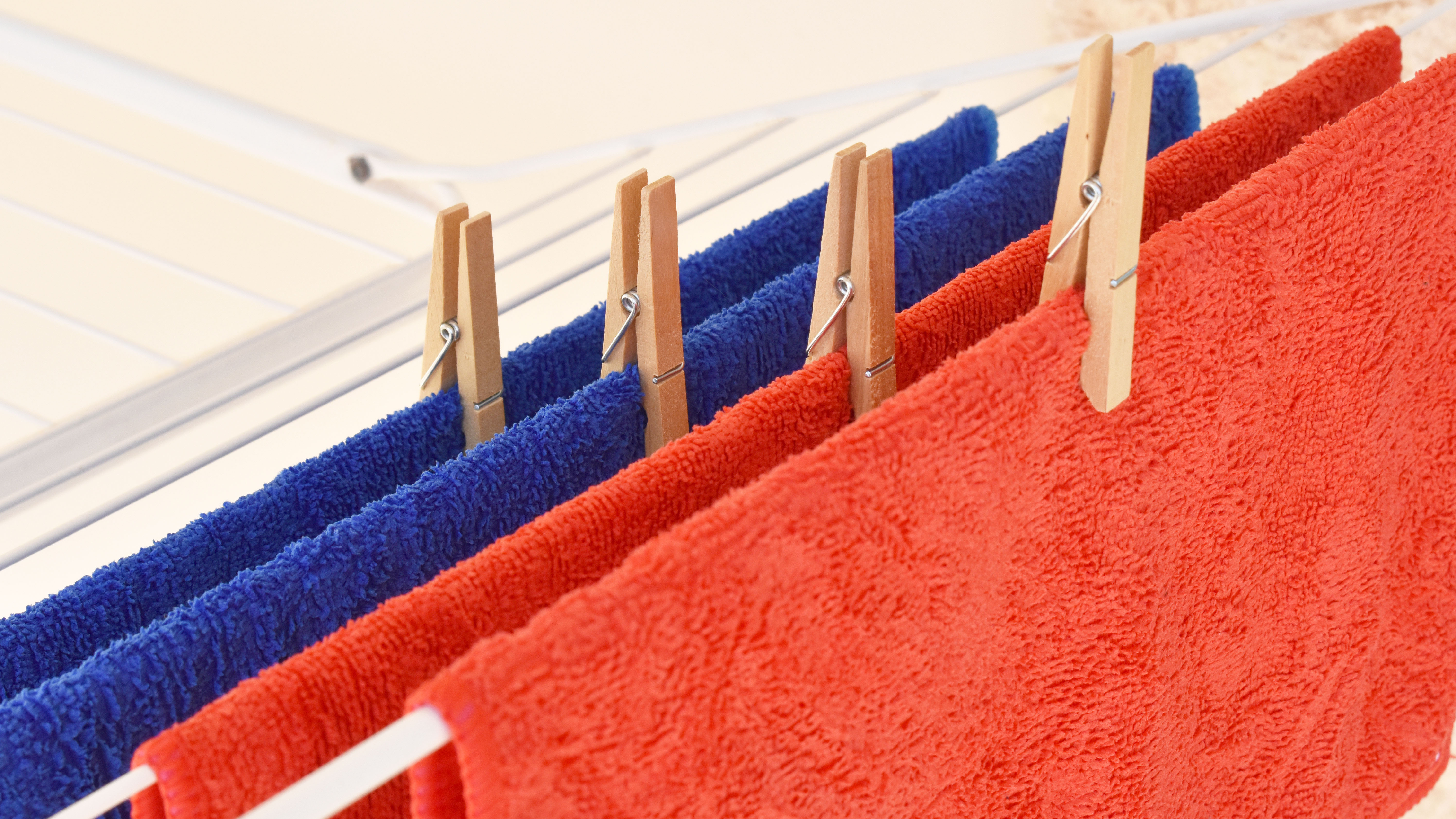 Red and blue microfiber cloths hanging to dry on a clothes line with pegs