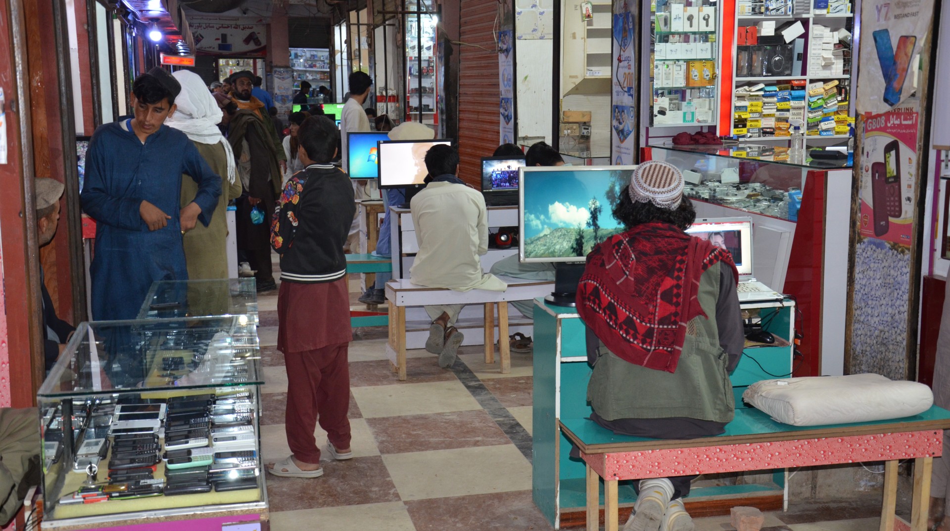 KHOST, AFGHANISTAN- OCTOBER 28: In Khost's Hammam Market, customers upload to their mobile phones videos of Taliban fighters, their songs, and other videos that related to the Taliban, in Khost, Afghanistan on October 28, 2021. 