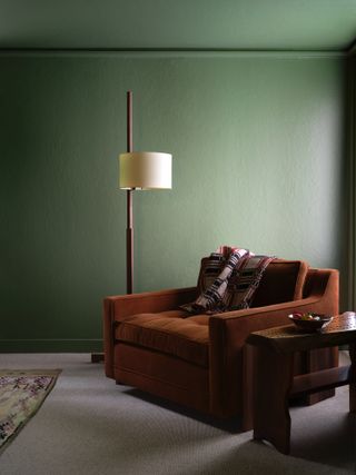 A living room with pistachio walls, and a brown sofa