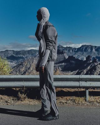 Man in running gear with hood up on mountain road