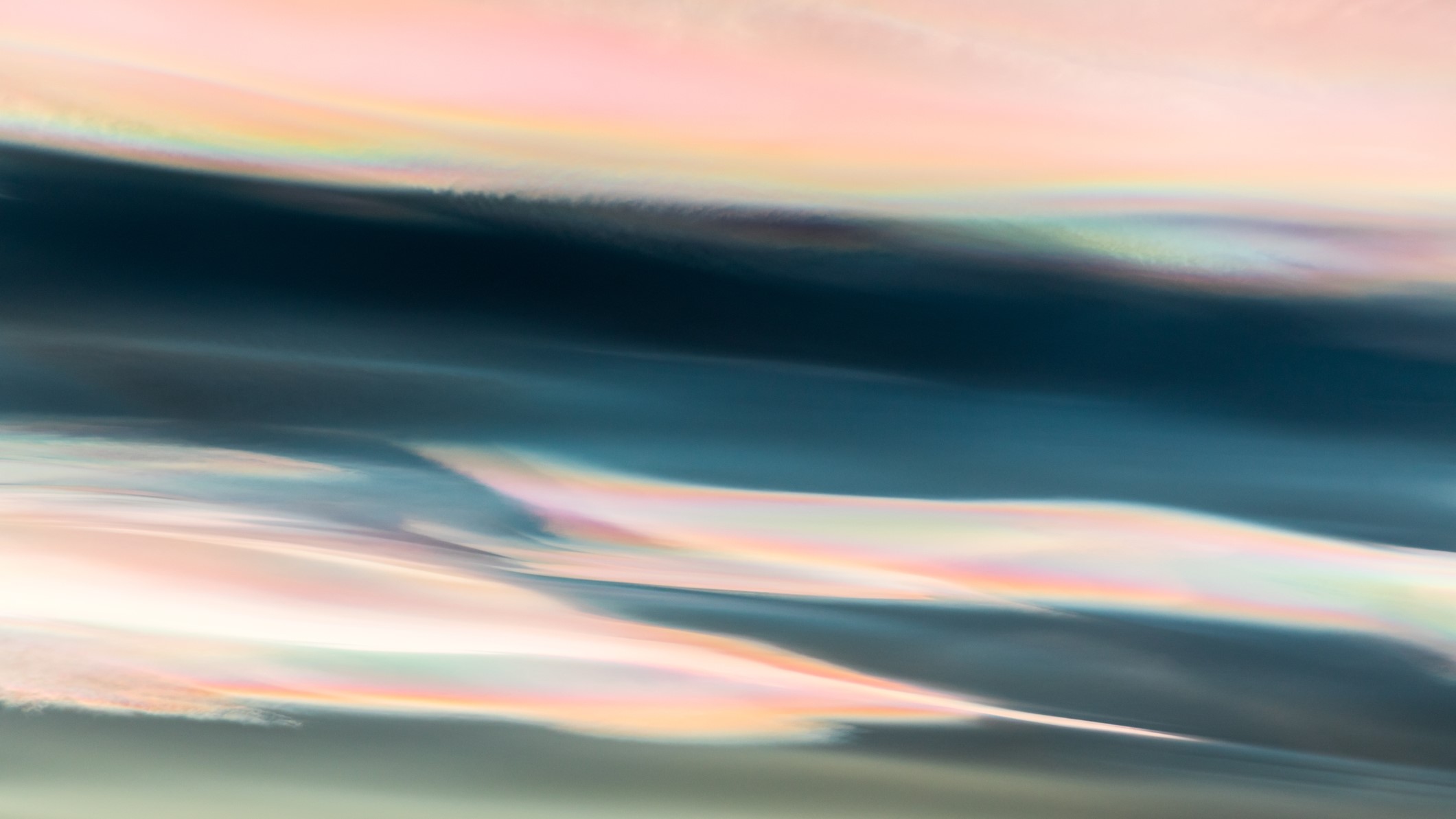 close up photograph of nacreous clouds shining pastel colors of pink, orange, yellow, blue, purple and green.
