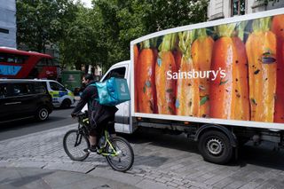 Deliveroo rider next to a Sainsbury's van