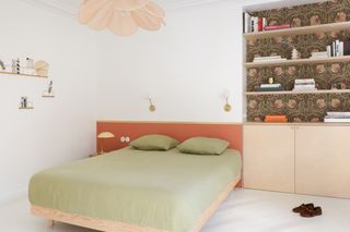 a neutral bedroom, with orange headboard and white, empty flooring