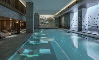 Interior view of Four Seasons Hotel, Kyoto, Japan featuring grey flooring, walls with a block design of rectangles in various sizes, pillars, a swimming pool and lounge chairs