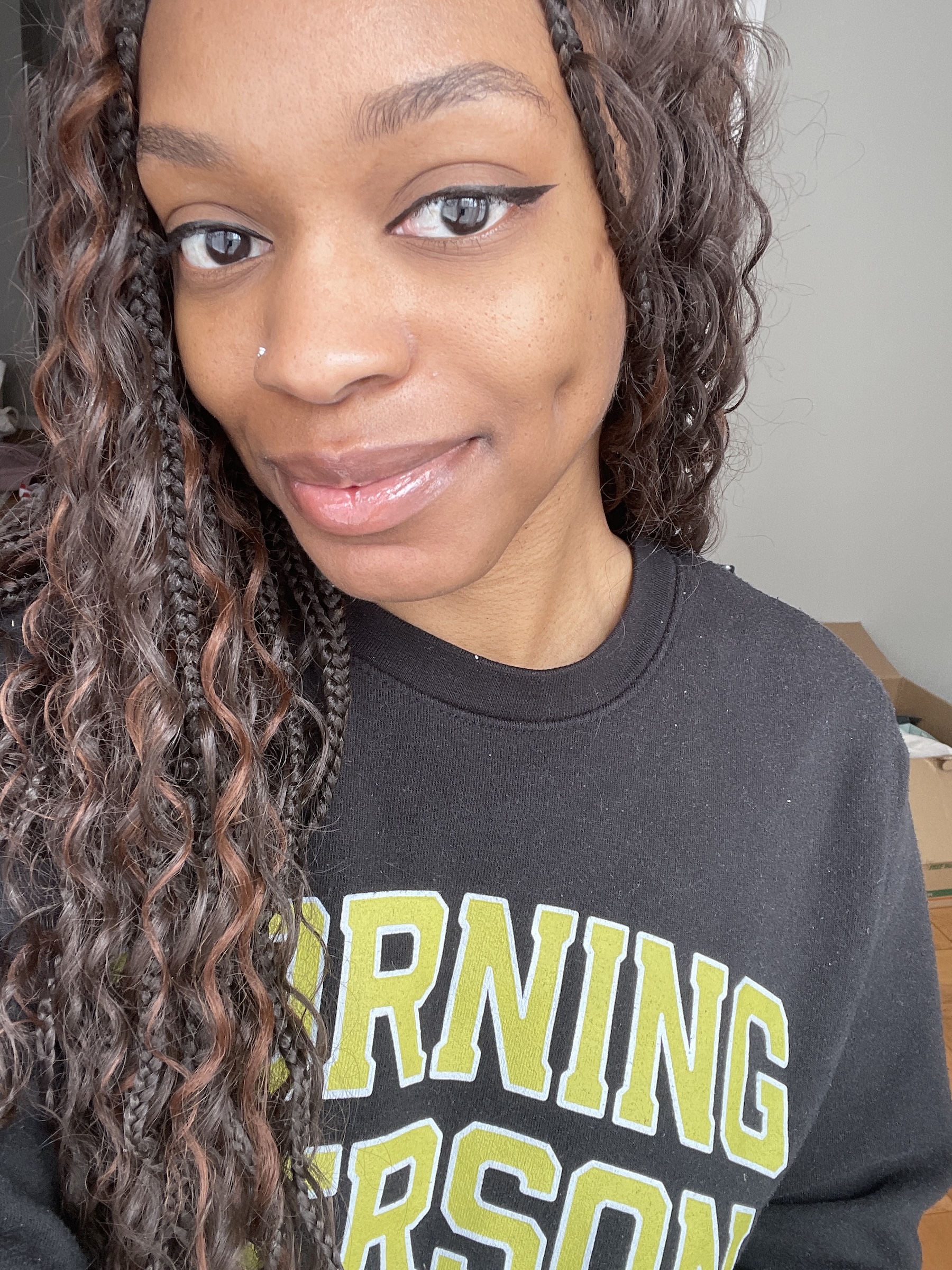 a black woman with dark brown braids wearing a black sweatshirt with lime green text