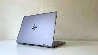 The HP Envy x360 2-in-1 seen from the back on a white desk