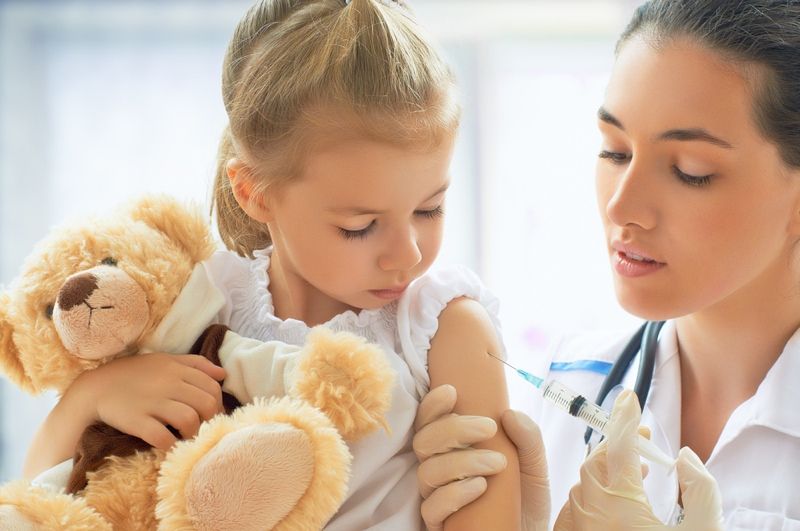 Doctor gives a little girl a flu shot at the hospital.