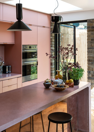 Pink cabinets with a pink concrete countertop, with a coordinating minimalist kitchen island