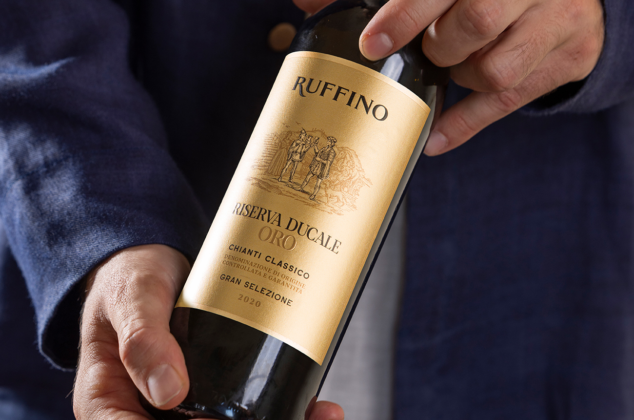 Close-up shot of hands holding a bottle of Ruffino Riserva Ducale Oro, a bottle of red wine with a gold label