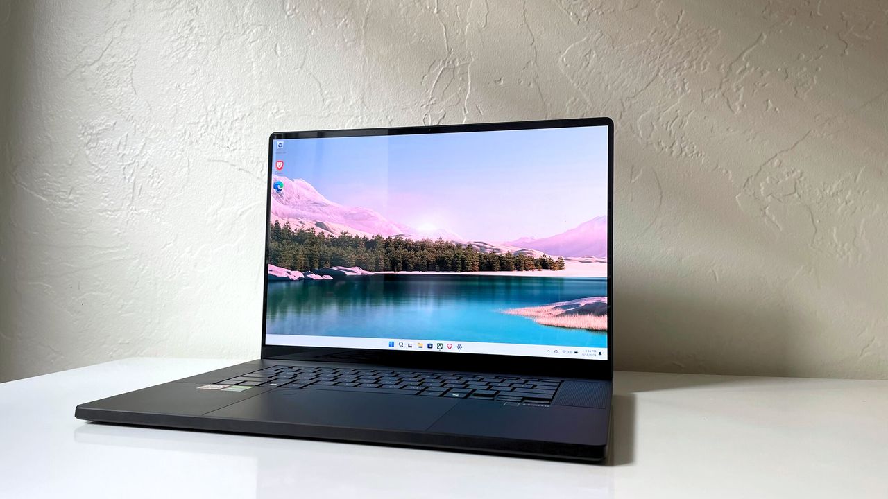 An open and powered on black laptop on top of a white table against a white wall.