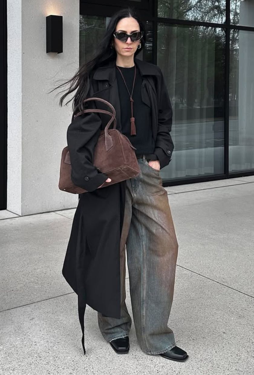 @ileniatoma_ wears a black trench, jumper, baggy jeans, black leather boots and a brown bowling bag