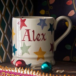 Ceramic white mug with multicoloured stars and the name Alex on it 