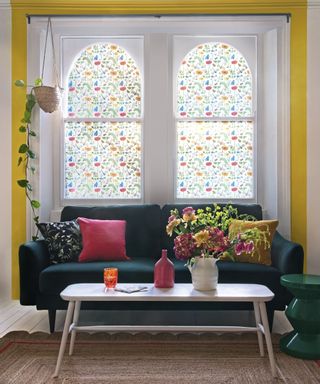 A living room with yellow wall paint decor and two windows with printed window film decor
