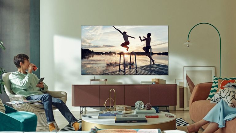 Samsung TV mounted on living room wall, while a young man watches from a chair