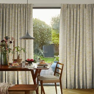 Golden patterned curtains next to wooden dining table