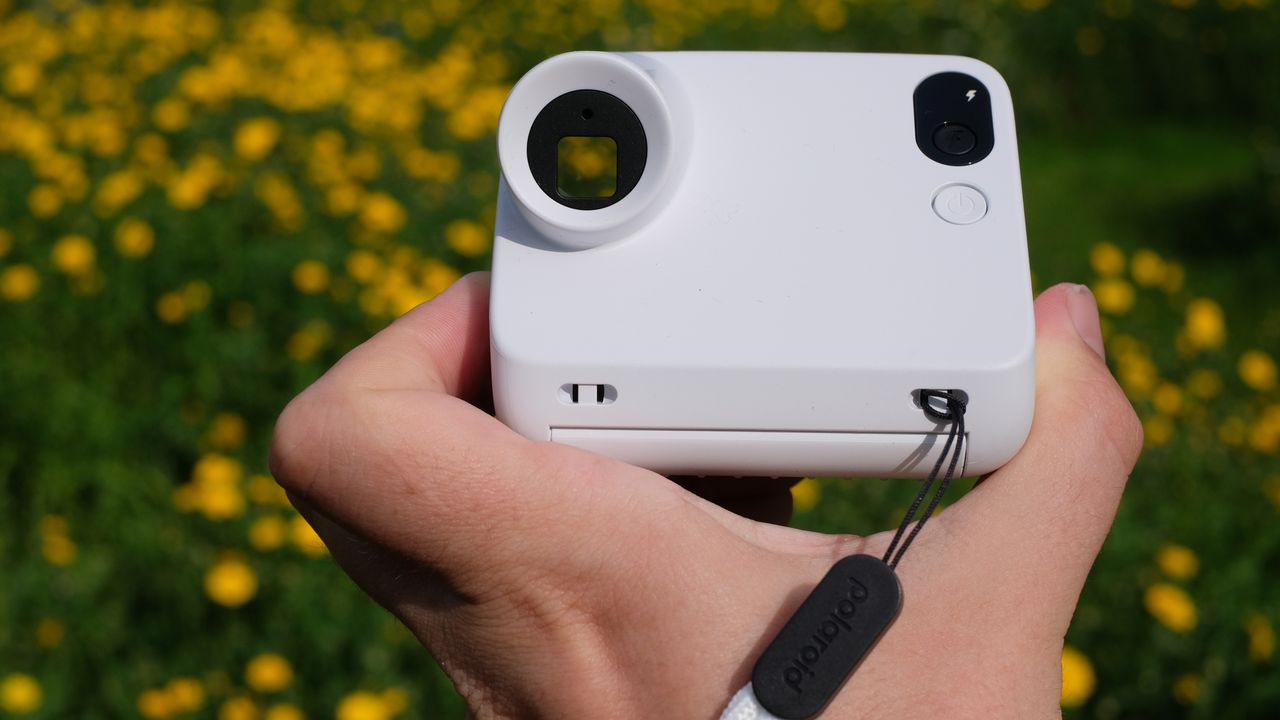 Photograph of man's hand holding Polaroid Go Gen 3 camera in white