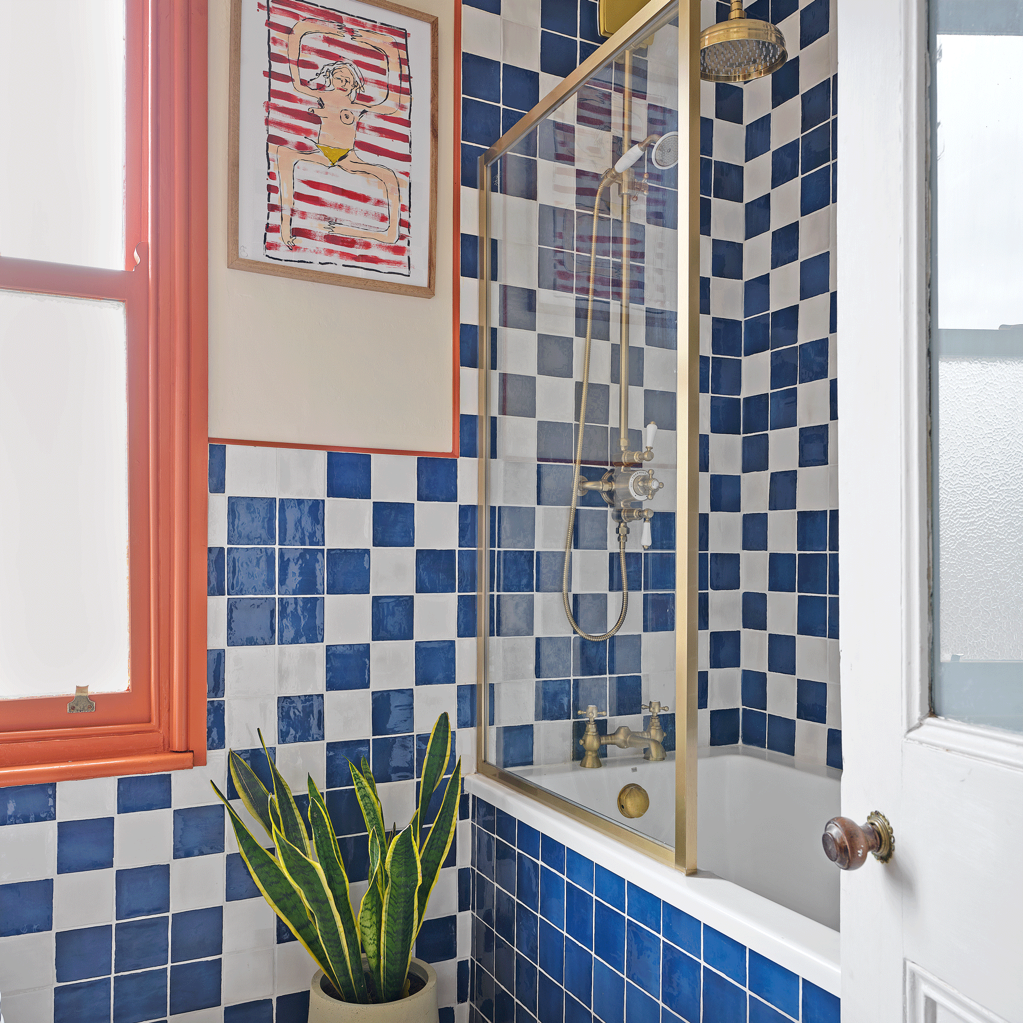 an orange and blue bathroom with blue and white checkered tiles with a shower bath and a glass screen