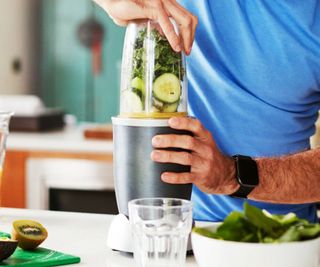 Nutribullet Pro 900 on a countertop with a man in a blue top about to blend